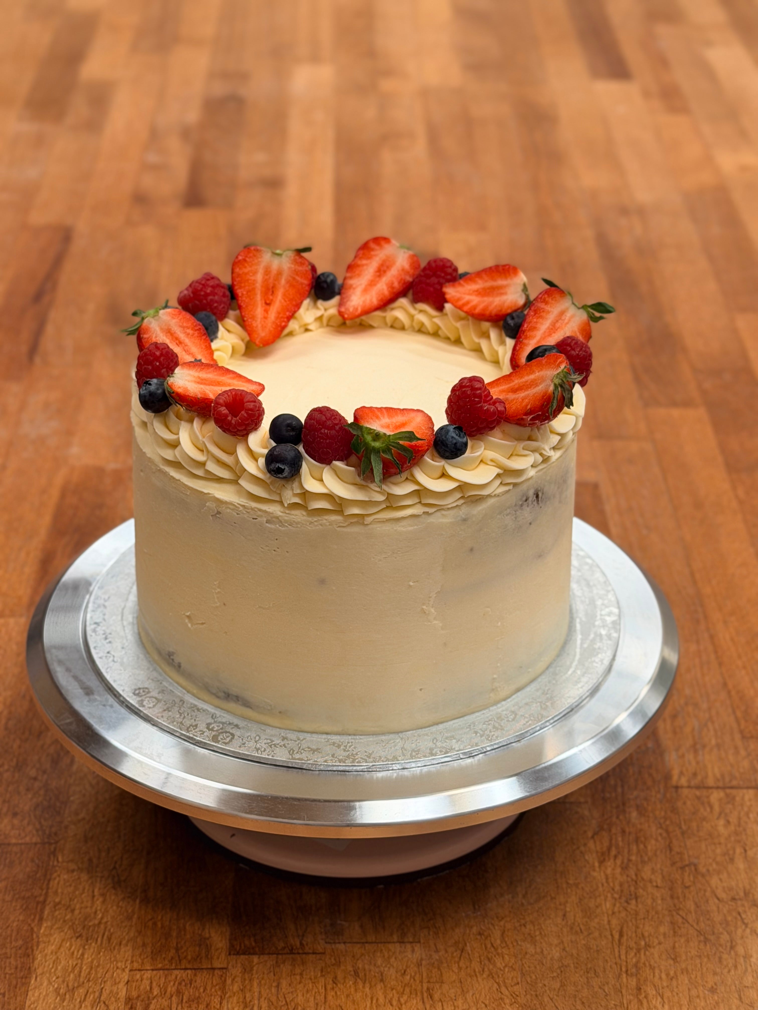 Victoria sponge cake topped with berries on a wood background